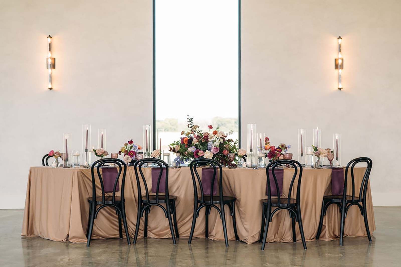 Elegant banquet table with pink linens, candles, and a floral centerpiece in a bright venue