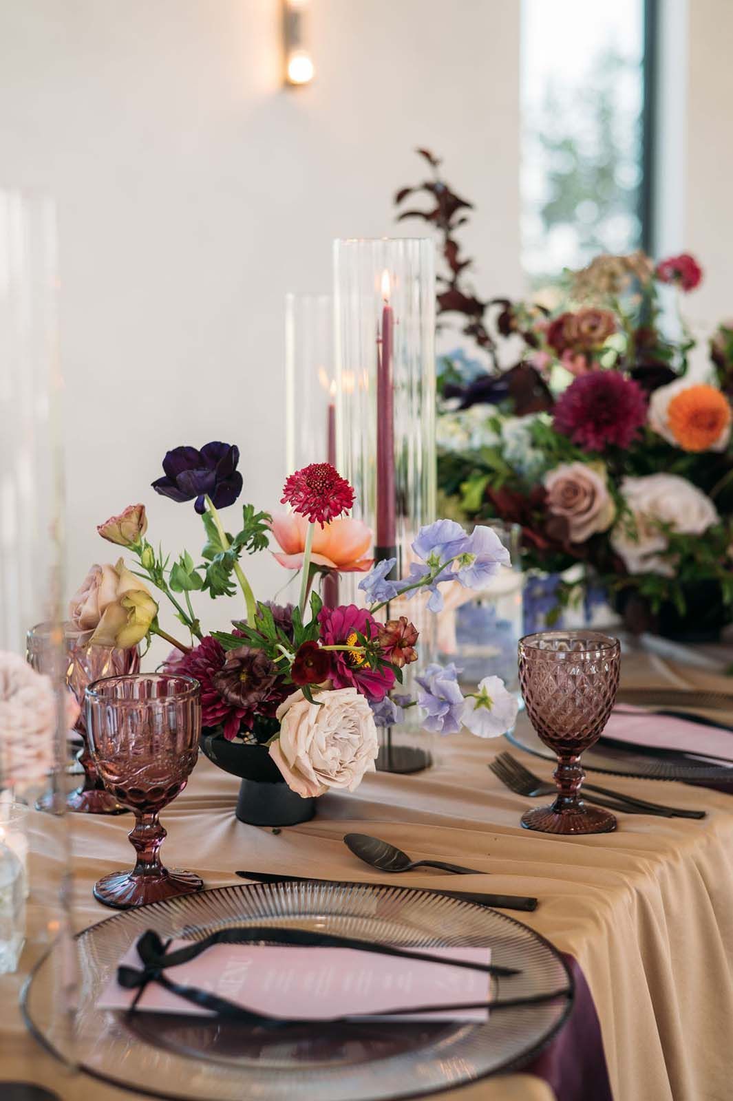 Elegant banquet table with pastel floral centerpiece, candles, and glassware at a formal event