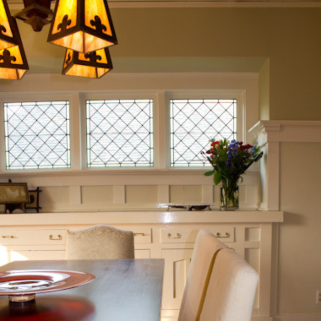 A dining room with a table and chairs and stained glass windows