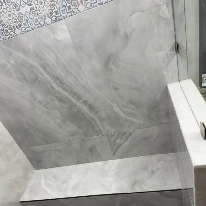 A shower featuring large, marbled grey wall tiles and a horizontal strip of patterned, decorative grey-and-white tiles.