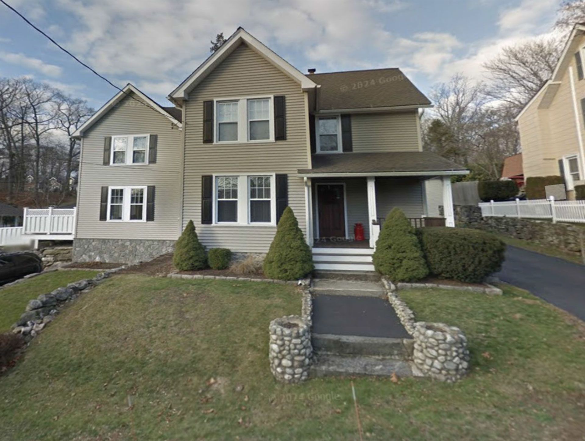 Two-story house with grey siding and black shutters, pathway to the front door.