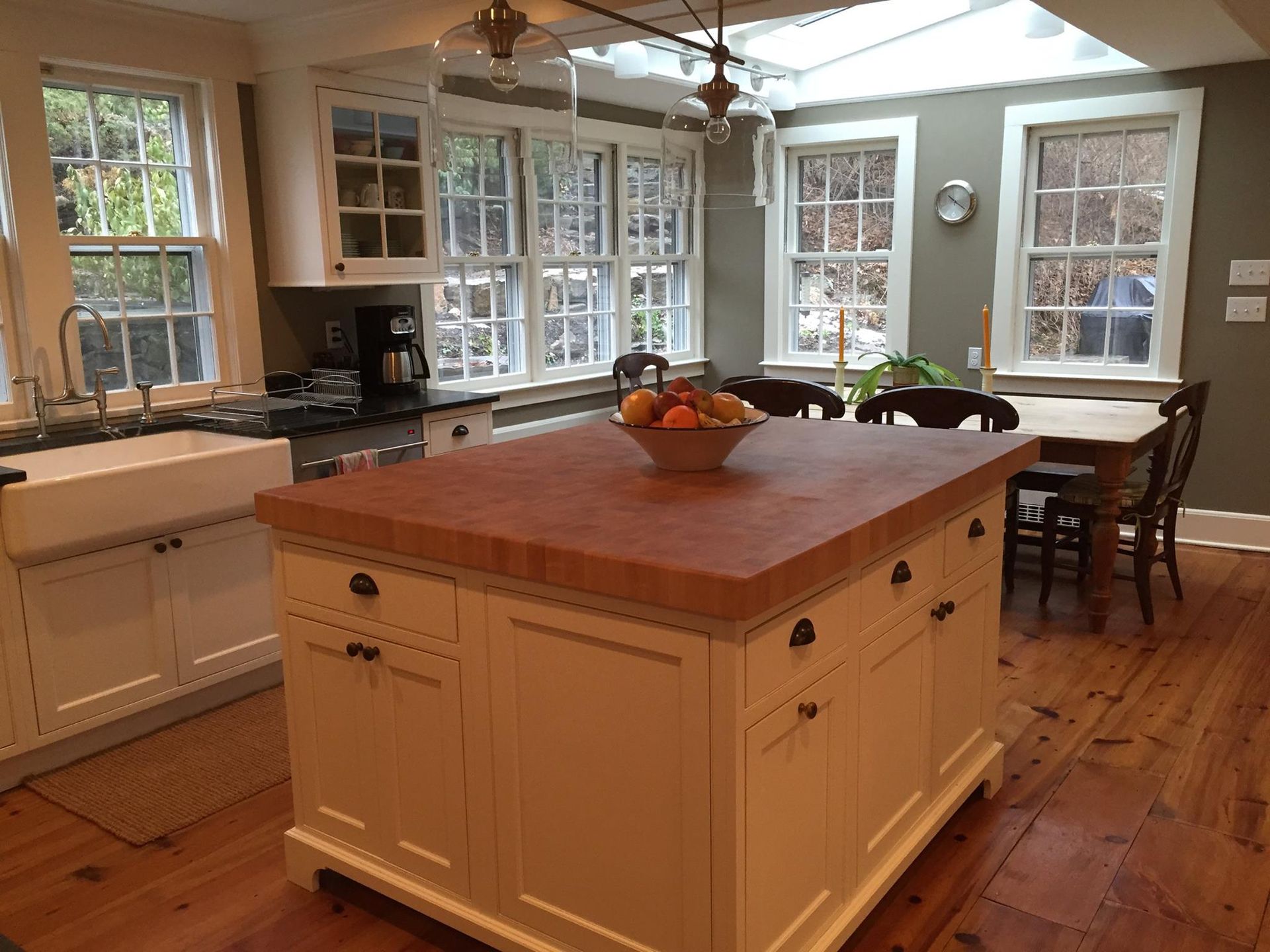 Custom Kitchen Remodeling Kitchen with white cabinets, butcher block island, windows, and a dining table.