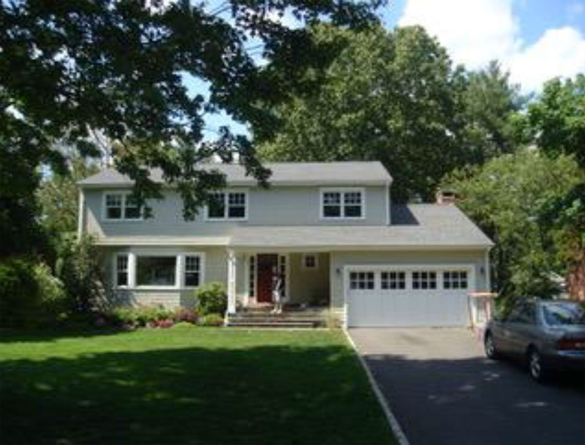 Two-story house with light gray siding, white trim, and a garage. A car sits in the driveway.