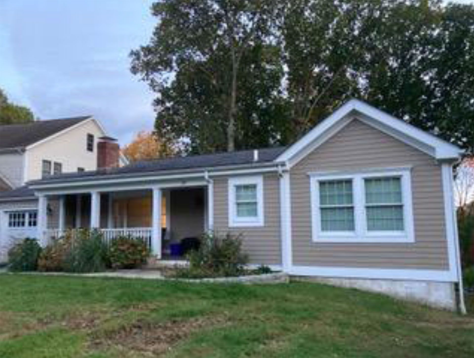 Tan house with white trim, porch, and lawn.