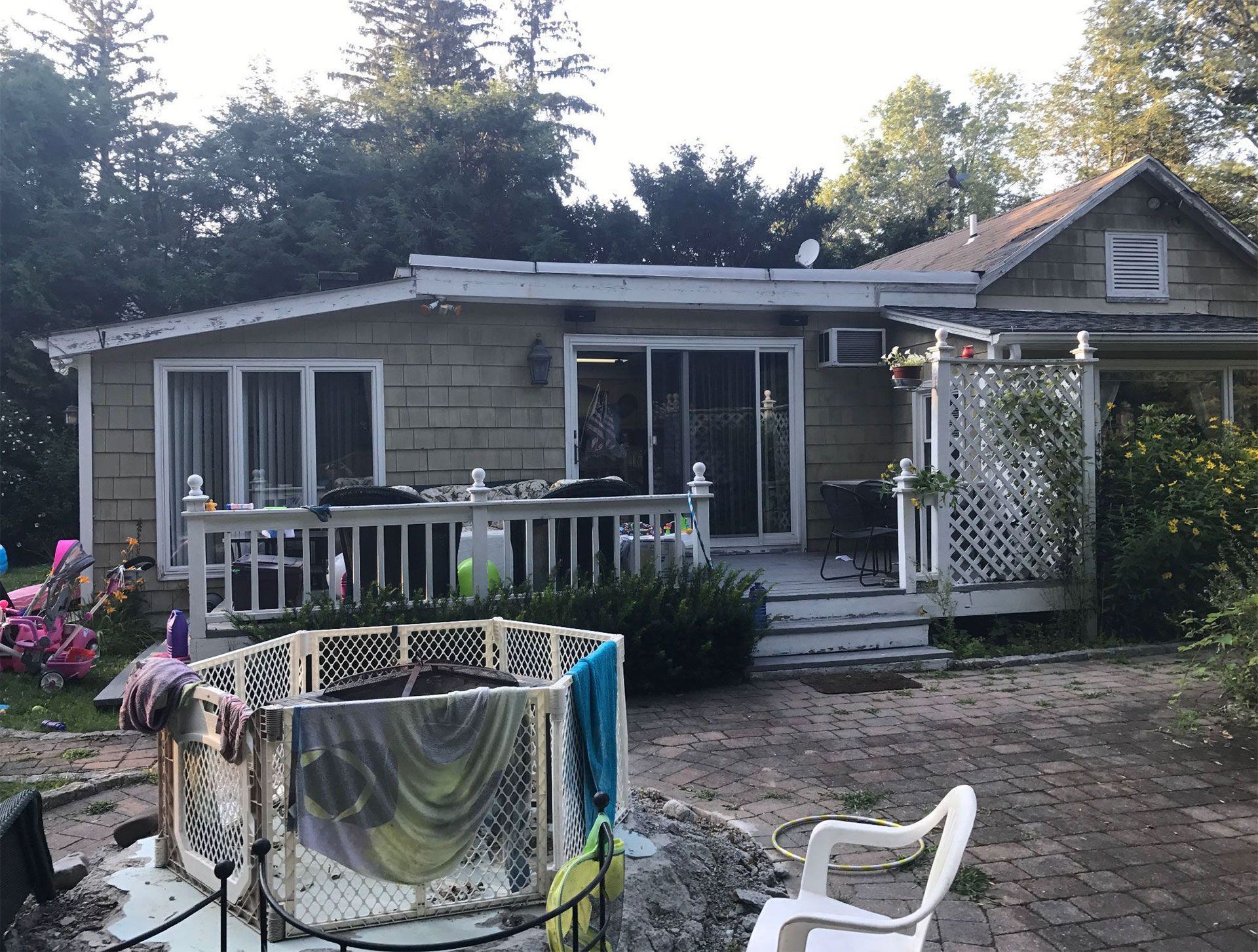 Backyard of a house with a deck, a child's pool, and a white plastic chair.