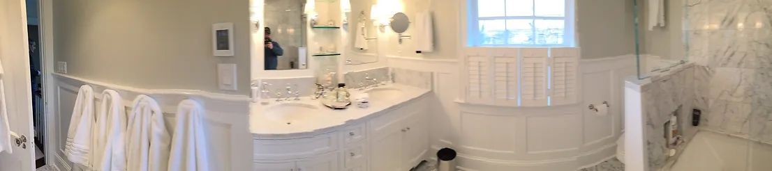 Elegant white bathroom with marble finishes, towels, and a window.