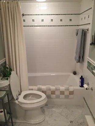 Bathroom with white tile, a toilet, tub, shower curtain, and a towel rack.