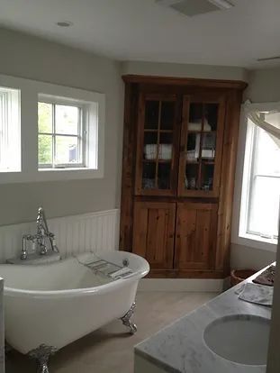 Bathroom with a claw-foot tub, wood cabinet, windows, and a marble countertop with a sink.