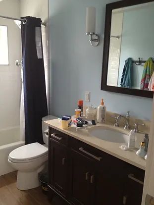 Bathroom with a dark brown vanity, blue walls, a toilet, and a shower with a blue curtain.