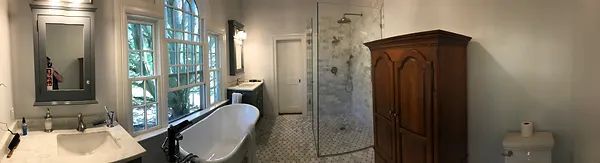Bathroom with a large wooden cabinet, a clawfoot tub, and a shower. A sink with a mirror is on the left.