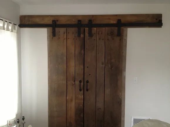 Barn-style wooden sliding doors, with black hardware, on white wall.