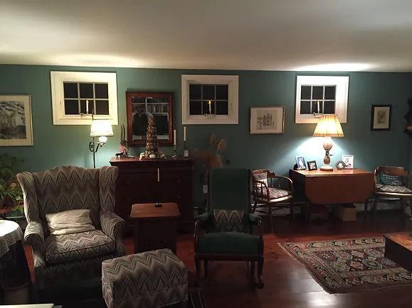  living room with teal walls, antique furniture, and rugs. 