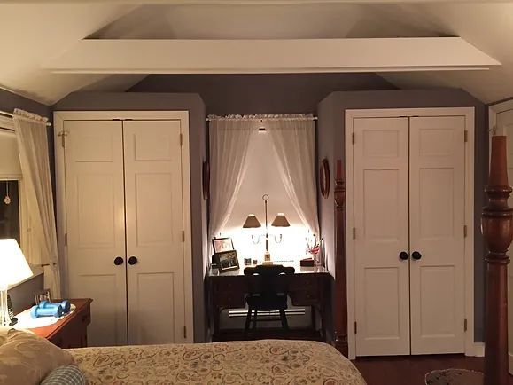 Bedroom with two white closets flanking a desk with window, gray walls, and white curtains.