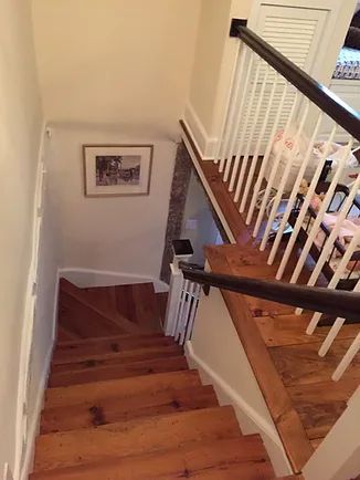 Wooden staircase leading down with a white railing and a framed picture on the wall.