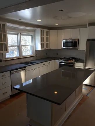 Newly renovated kitchen with white cabinets, gray countertops, and an island.