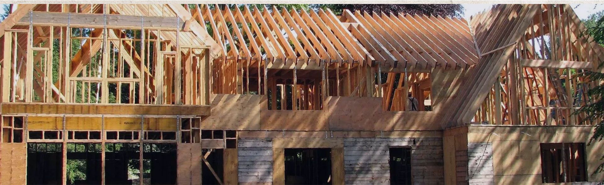 A house under construction, showing wooden frame with roof trusses.