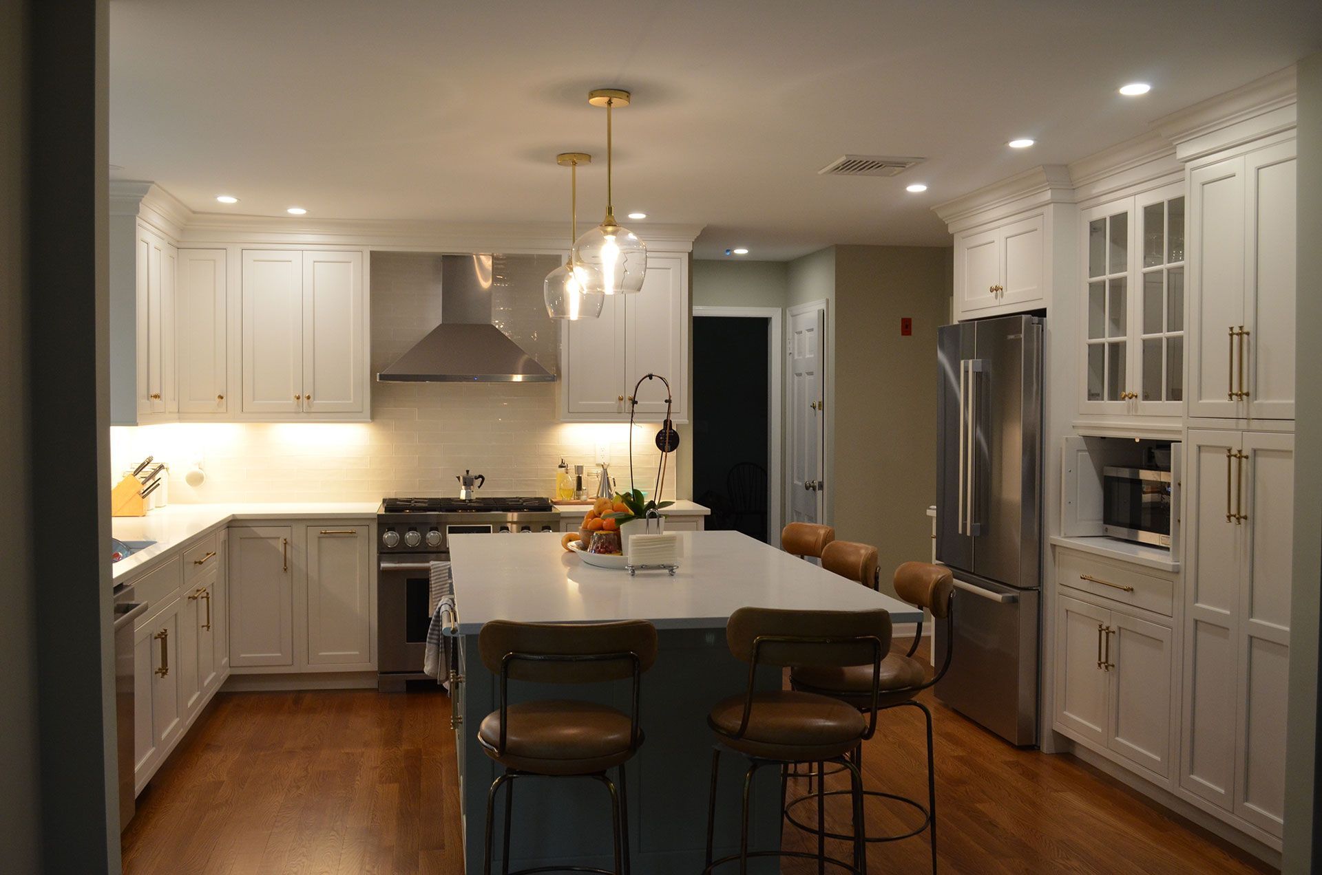 Bright, modern kitchen with white cabinets, large island, and stainless steel appliances.