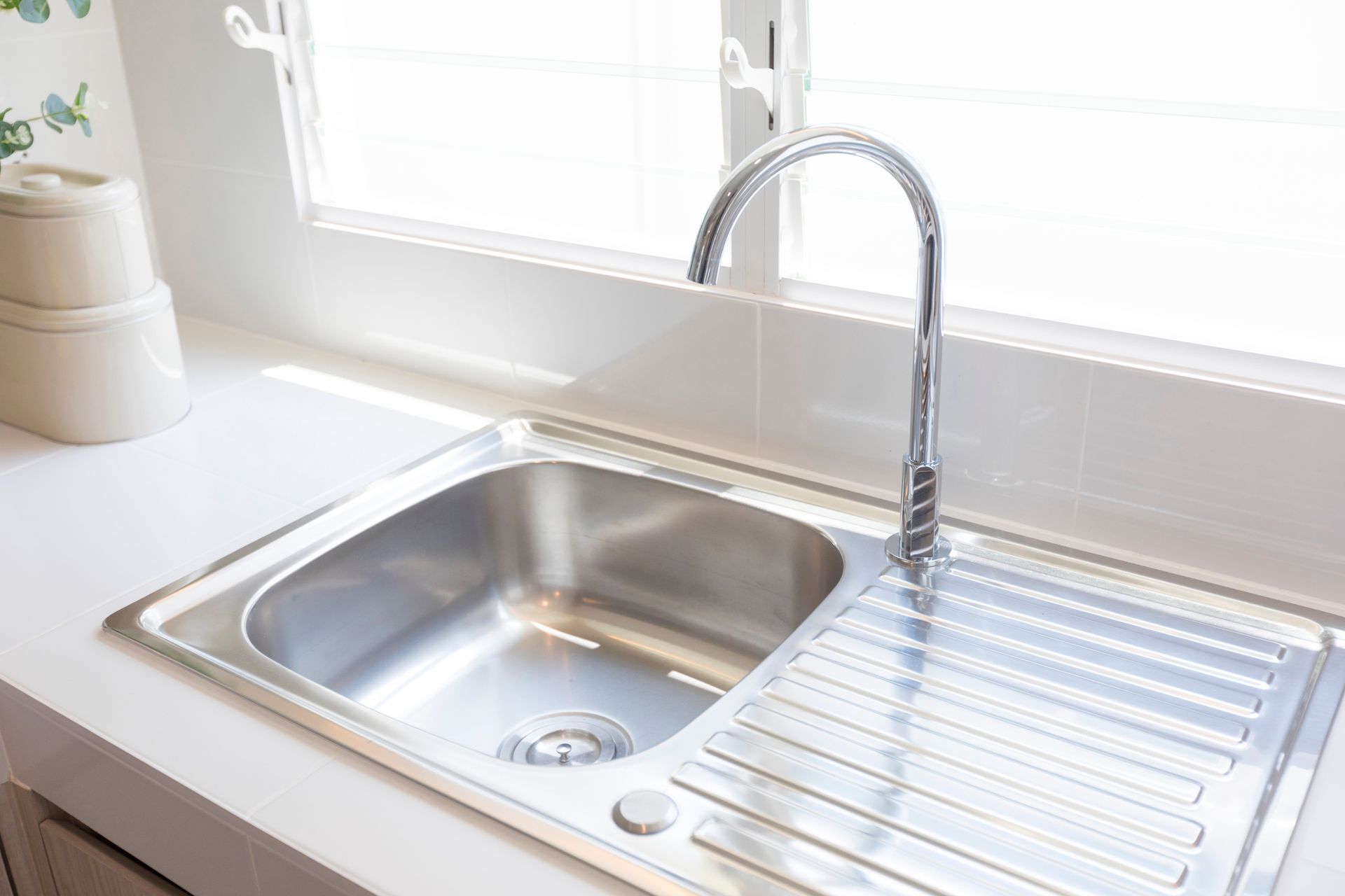 Bright kitchen sink with chrome faucet and white countertop by a sunny window