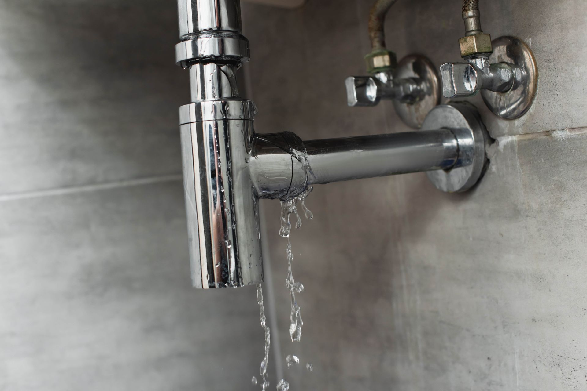 Chrome sink drain pipe leaking water under a bathroom sink