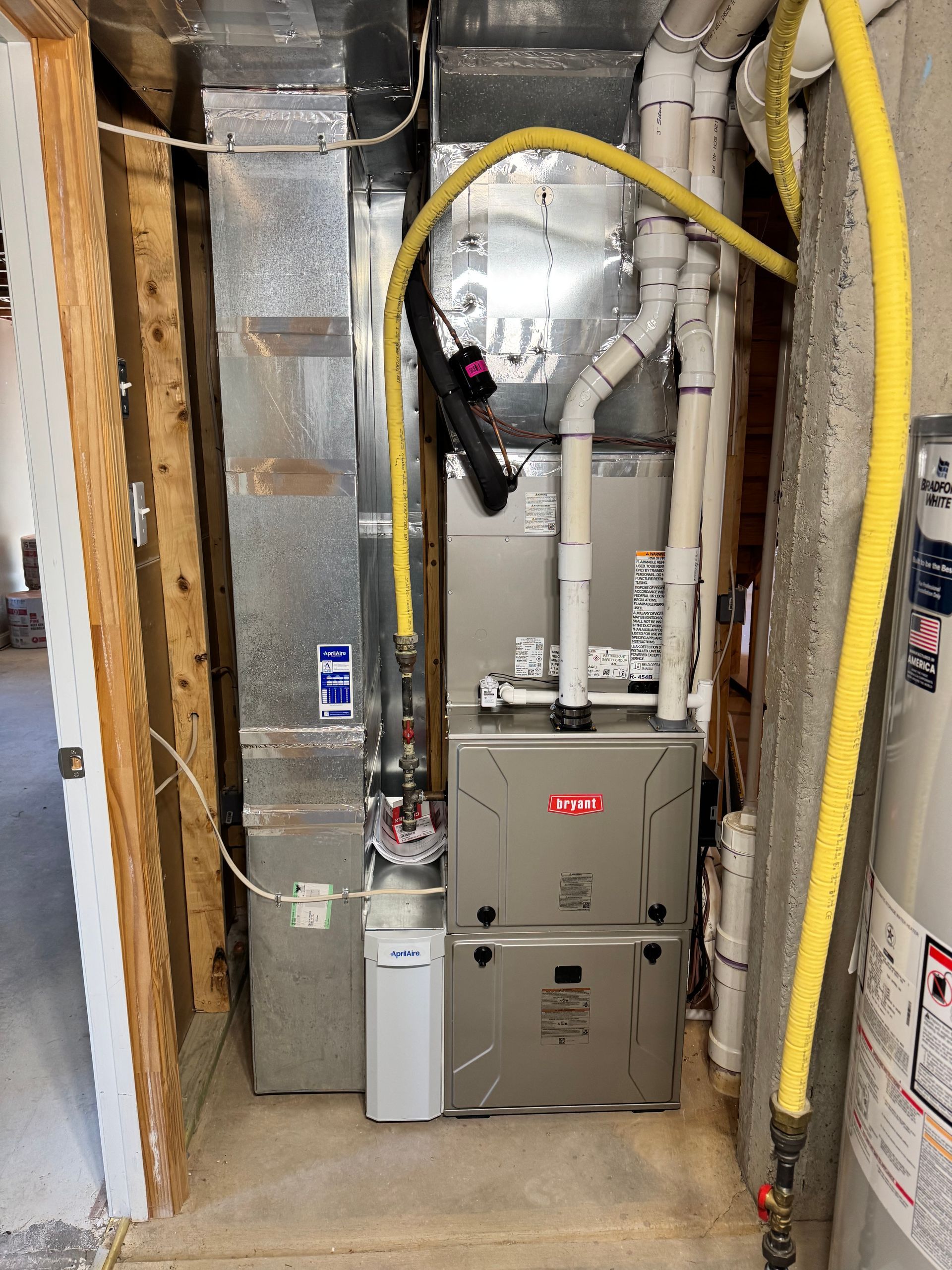 Utility closet with furnace and exposed ductwork in an unfinished basement.
