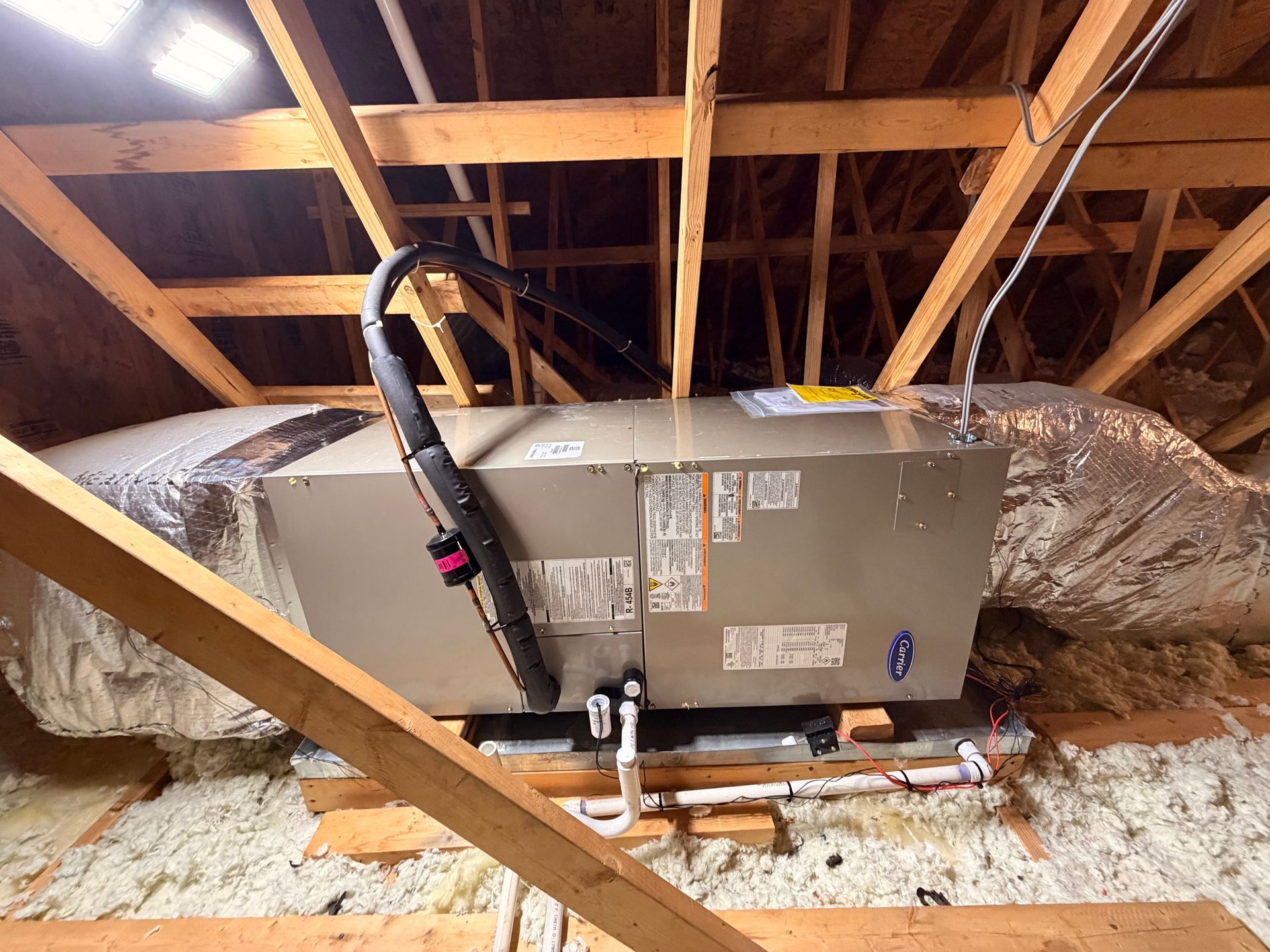 Attic HVAC unit with insulated ducts and exposed wooden rafters
