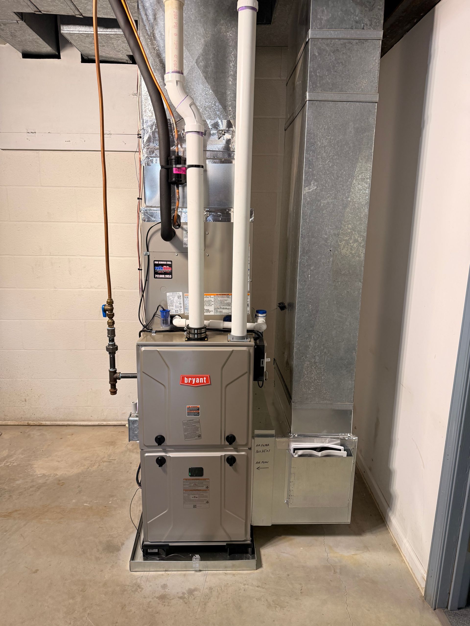 Furnace and HVAC ductwork in a basement utility room with beige walls and concrete floor