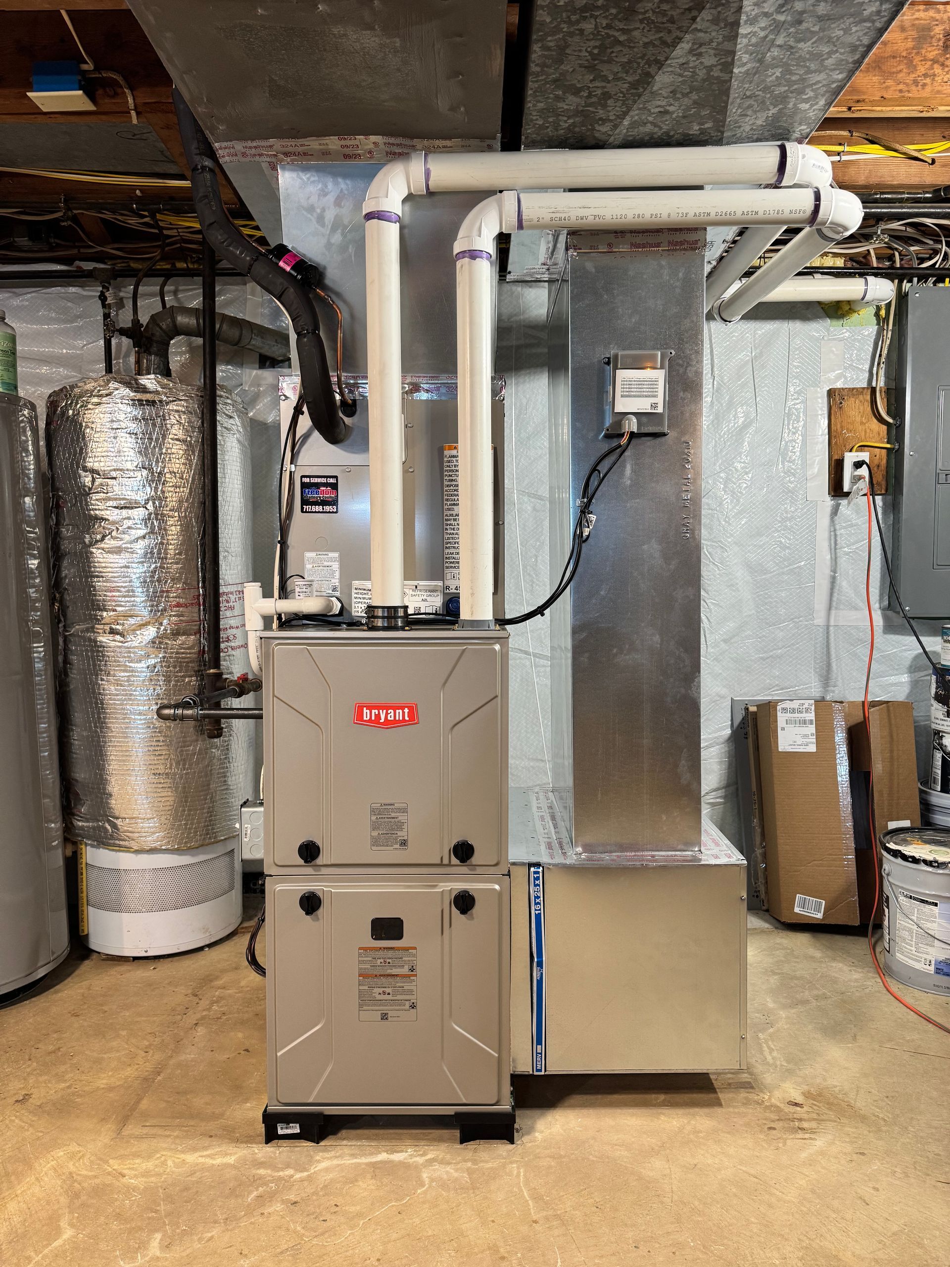 Basement HVAC furnace and ductwork with metal vents and insulated piping.