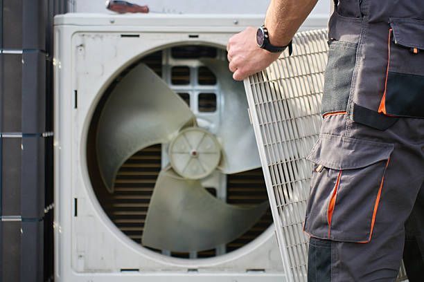 Technician installing an outdoor air conditioner unit in a utility area