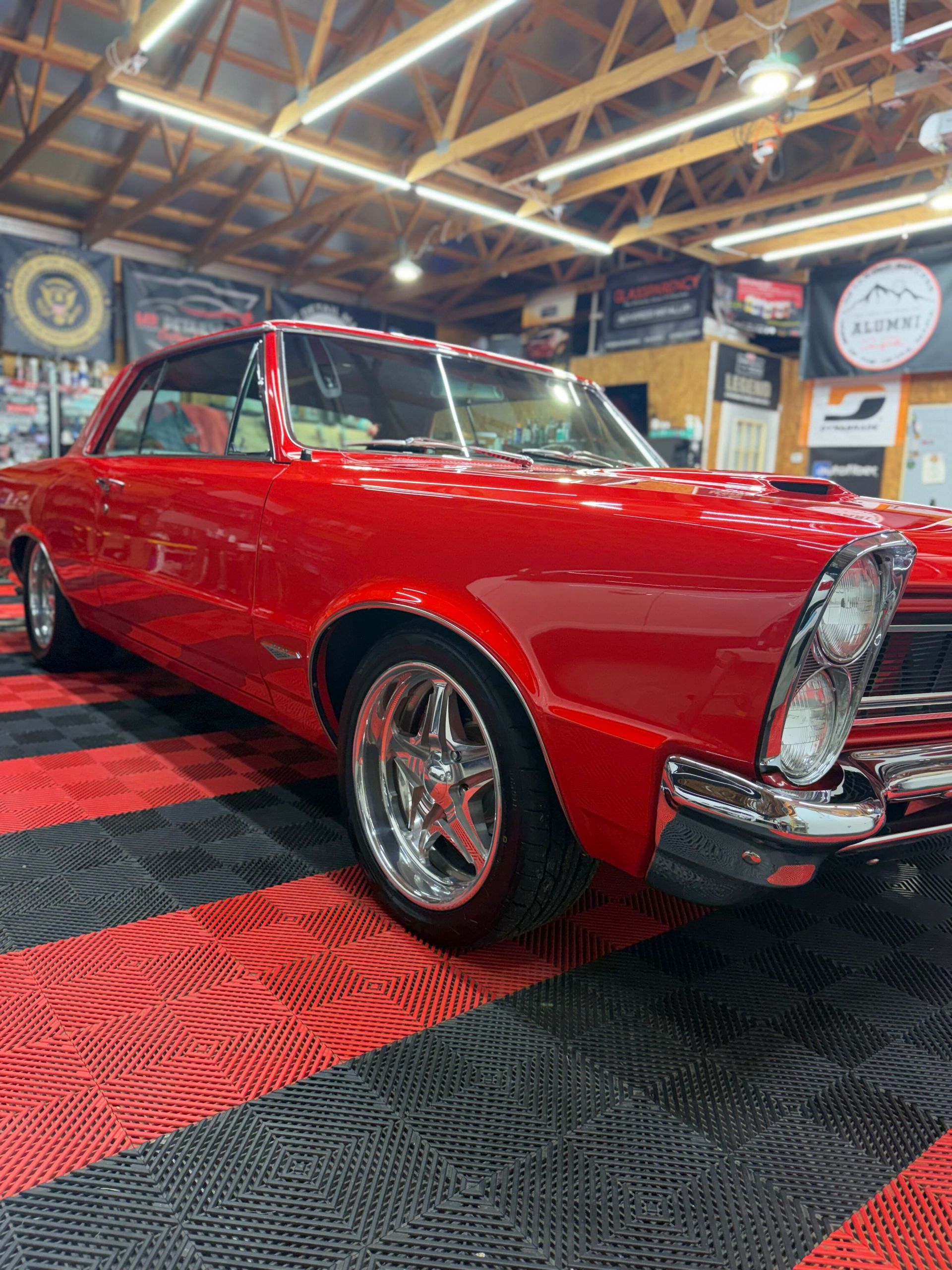 Red classic convertible car on display in an indoor showroom with checkered floor.