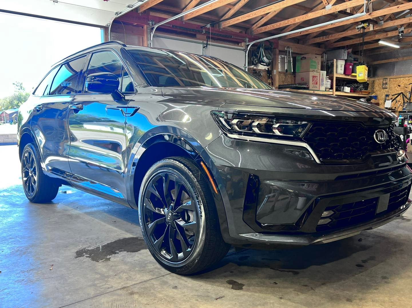 Gray Kia Sorento SUV with black rims parked inside a garage.