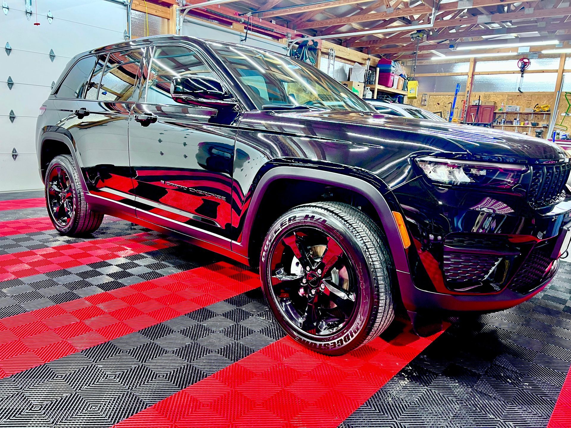 Black SUV on display at an auto show, with glossy paint and red accents on a red-and-black floor.