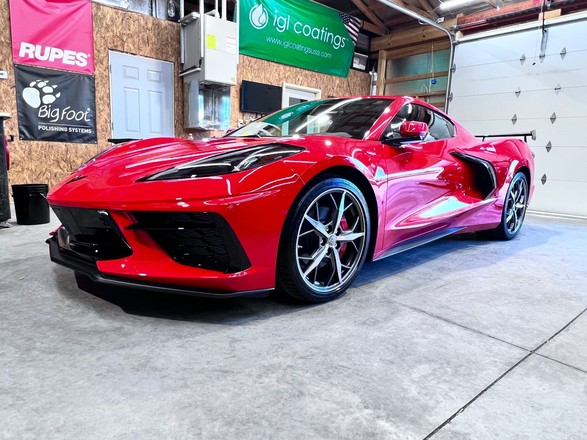 Red sports car in a garage, photographed from the front-left side.
