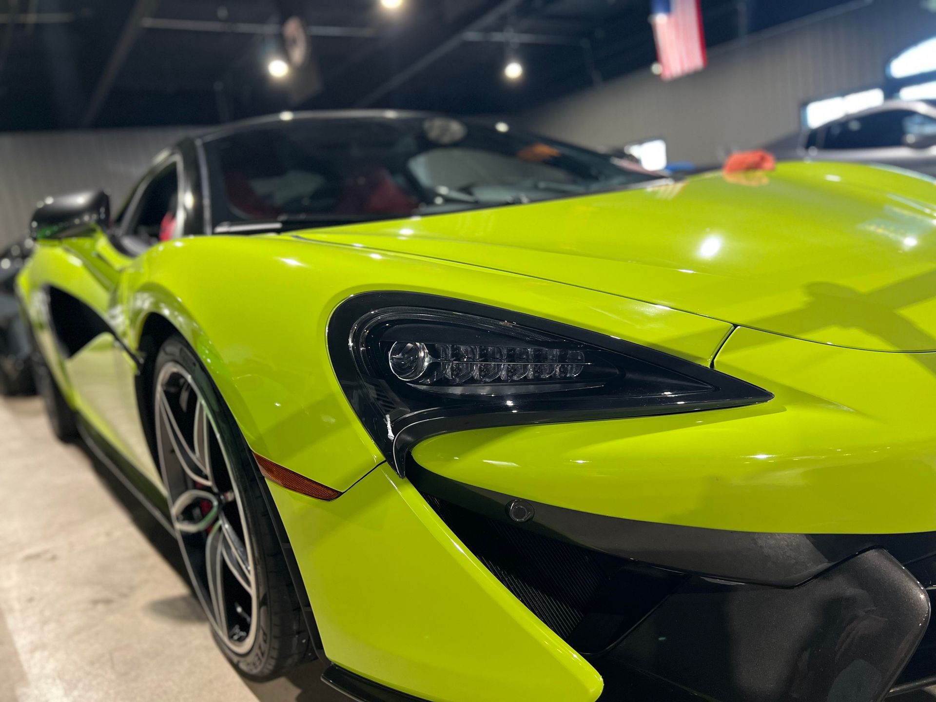 Bright green McLaren sports car in a showroom, black accents, sleek design.