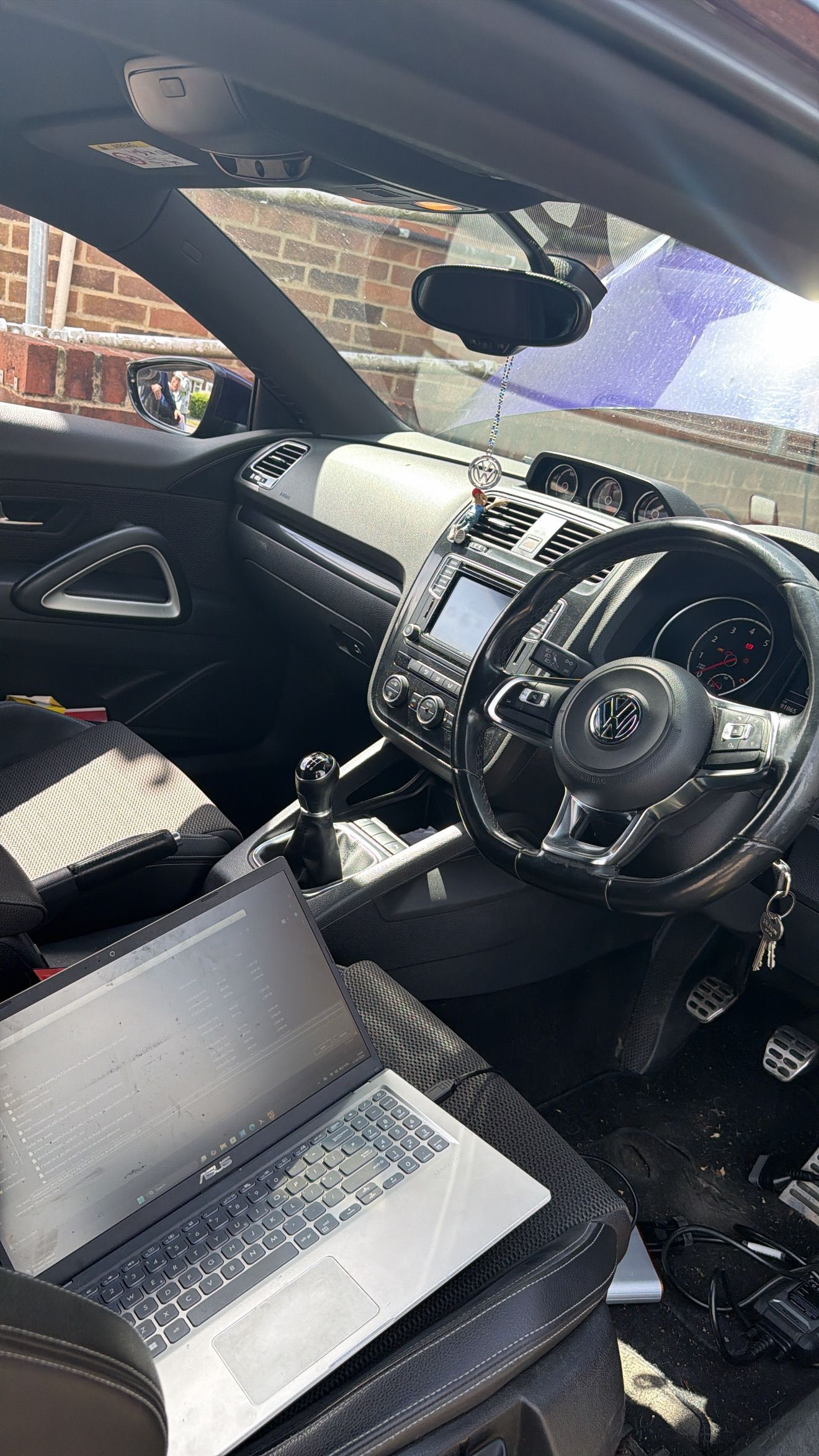 Car interior with black seats, dashboard, and steering wheel, viewed from the passenger side.