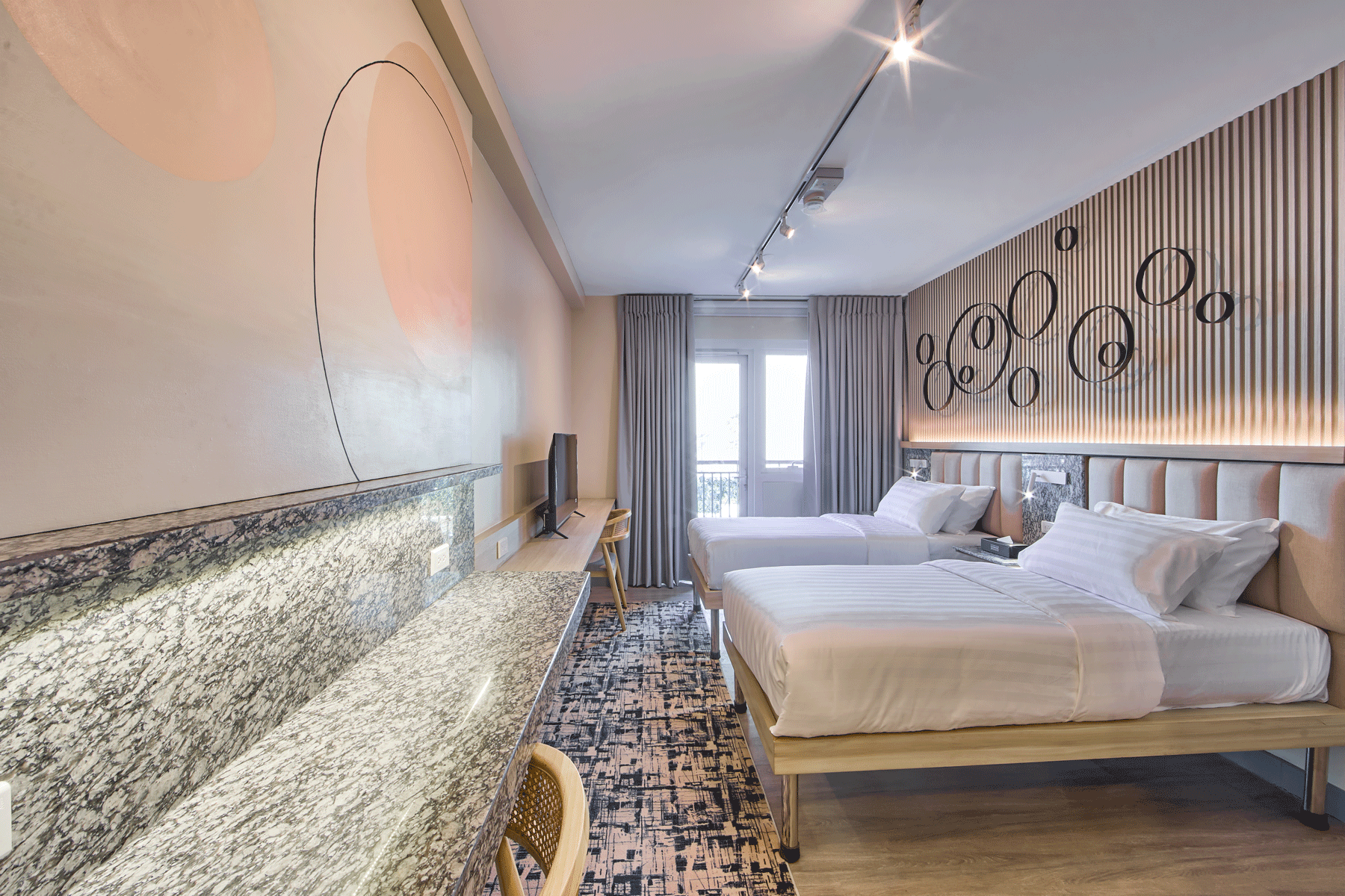 Modern twin bedroom at The Connor serviced apartments, featuring artistic wall design and balcony view near Greenhills