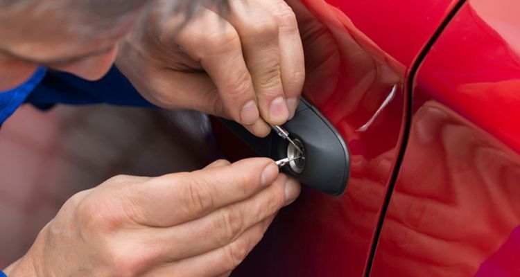 A man is locking a car door with a key.