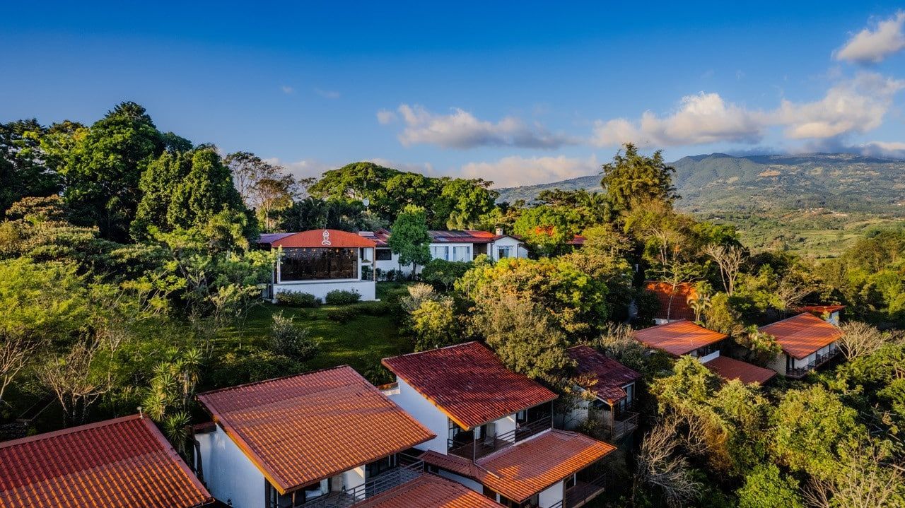 Red-roofed white cottages amid lush tropical greenery at sunset