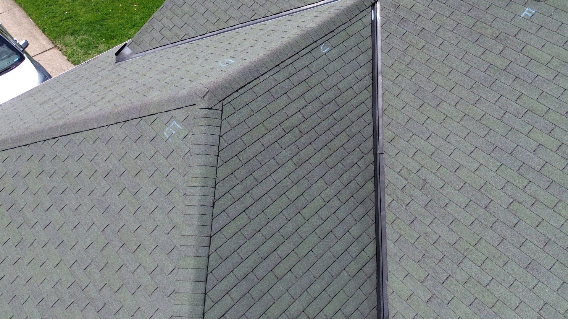 Gray shingled roof with a vertical ridge line and a small section of green lawn visible at the top left