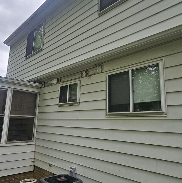 Side view of a light gray house with multiple windows and vinyl siding.