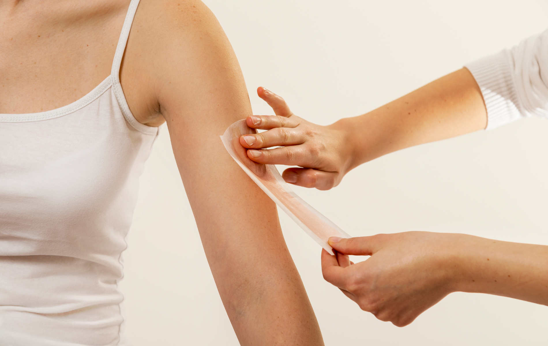 Person applying a bandage to an upper arm against a white background