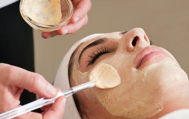 Facial spa treatment being applied with a brush to a client’s face