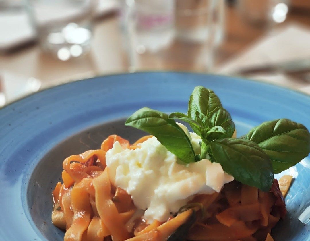 Un primo piano di un piatto di cibo con tagliatelle e basilico