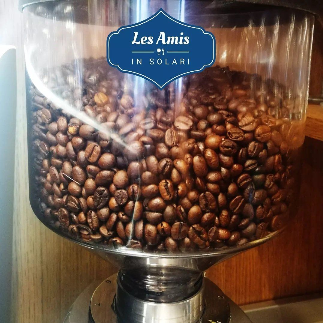 Un contenitore di vetro pieno di chicchi di caffè dice les amis in solari
