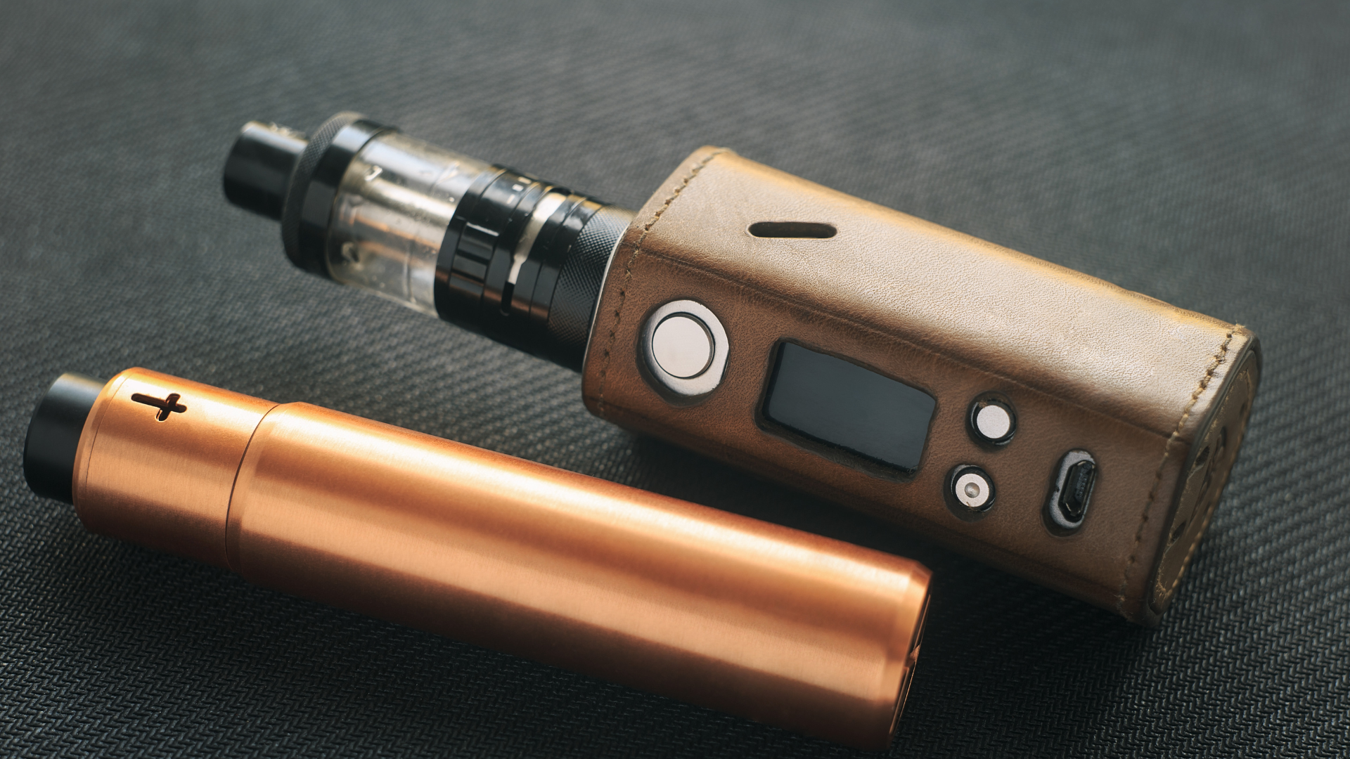 Two electronic cigarettes are sitting on a table.