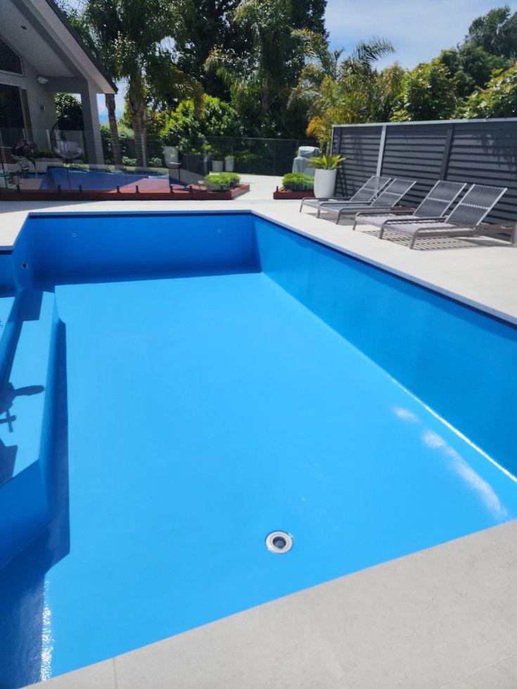 Empty blue swimming pool with gray concrete surround.