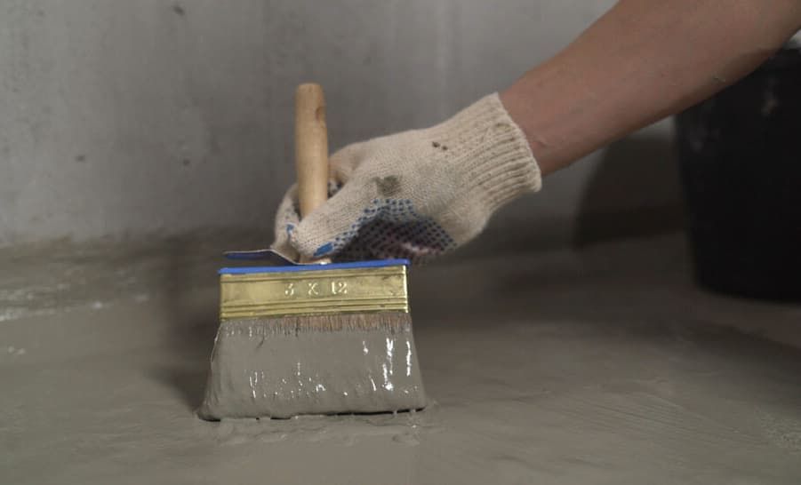 A Person Is Painting A Concrete Floor With A Brush — Greg Cannon Painting In New Castle, NSW