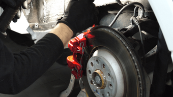 a mechanic doing a brake service wearing black gloves