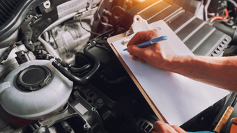 a mechanic writing notes during a vehicle inspection