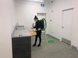 Commercial janitorial cleaning with backpack vacuum in utility washroom