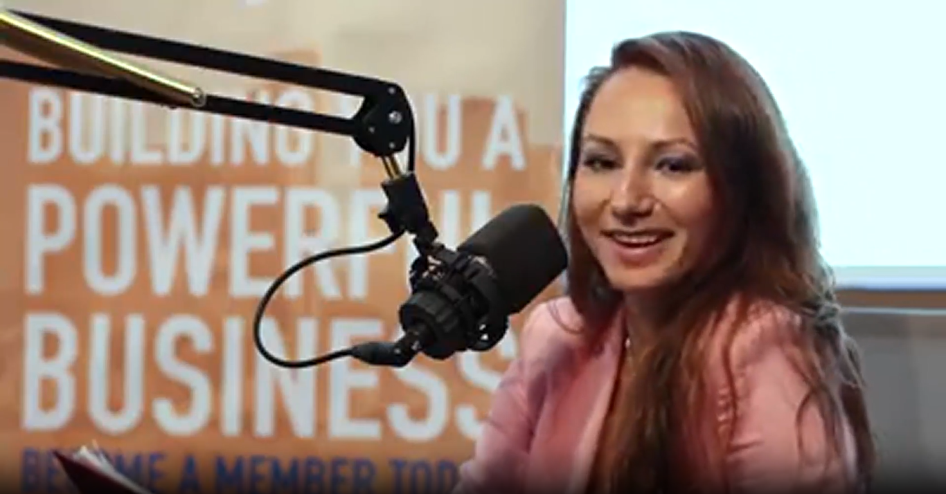 A woman is sitting in front of a microphone and smiling.